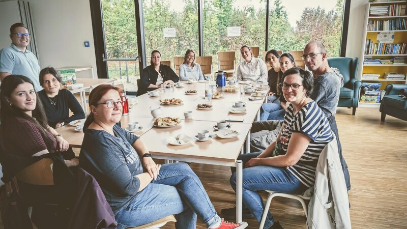 Elf Menschen sitzen an einem großen Tisch im Café.